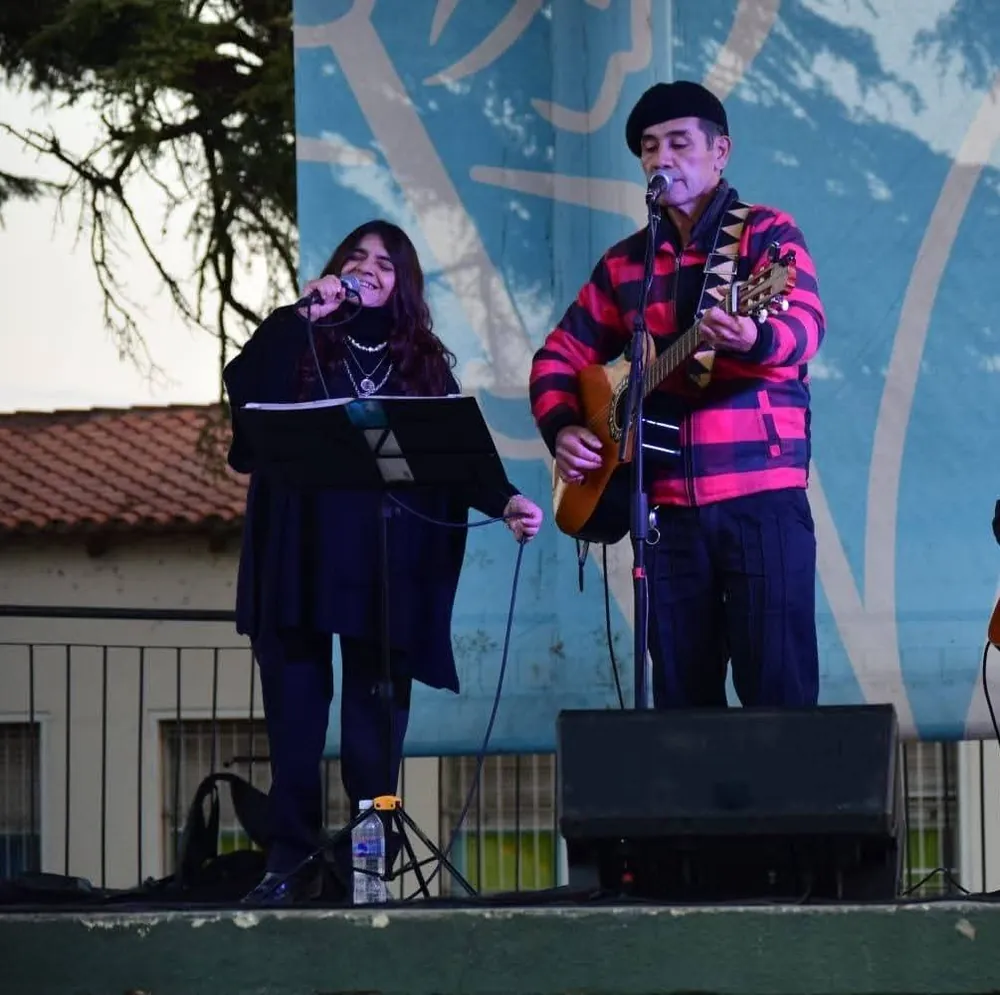 Lina y Eduardo cantando en dúo sobre el escenario, con guitarra criolla