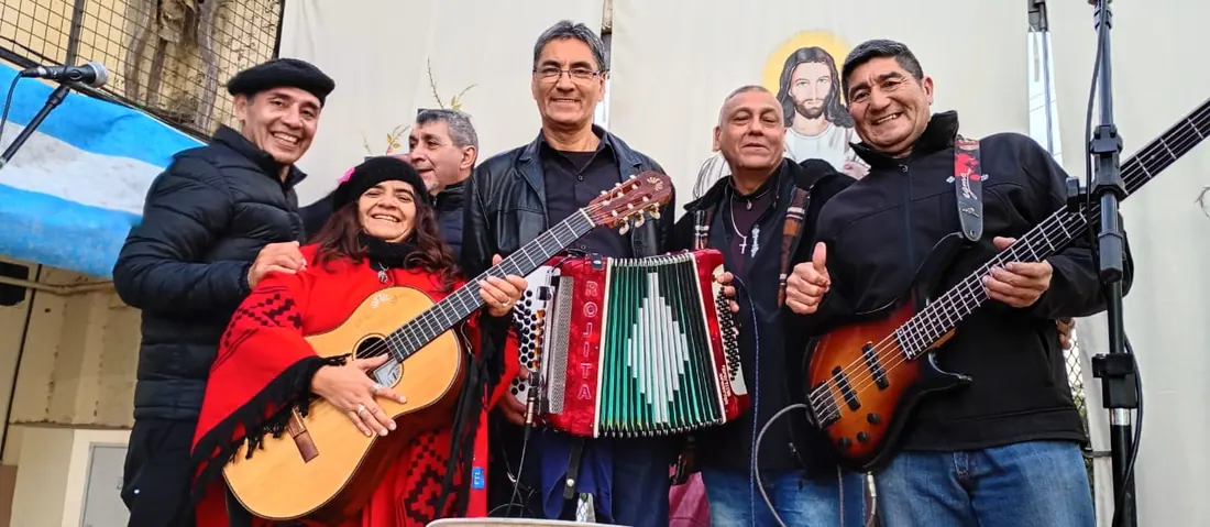 Músicos con guitarra, acordeón a piano y bajo posando en un escenario al aire libre
