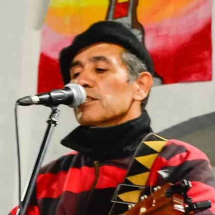 Retrato de Eduardo tocando la guitarra criolla con boina